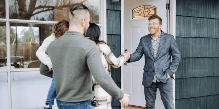 A man meets a family at the door of a house. Getting real estate agent advice is helpful.