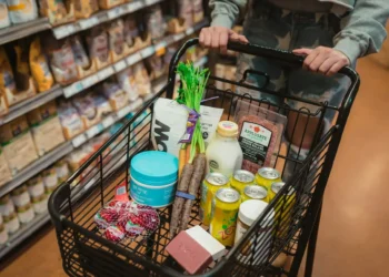Person pushes grocery cart full of food. Using thrifty grocery lists can save you money and help with meal planning.
