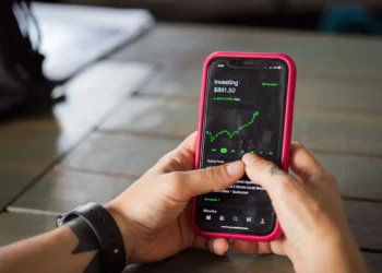 Two hands hold a phone. Starting investing is as simple as choosing a Roth IRA.