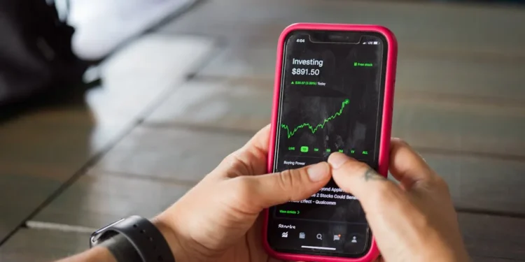 Two hands hold a phone. Starting investing is as simple as choosing a Roth IRA.