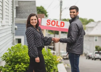 Two people shake hands in front of a SOLD sign. Is selling your home without a realtor worth it?
