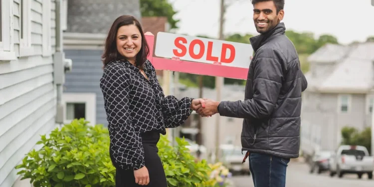 Two people shake hands in front of a SOLD sign. Is selling your home without a realtor worth it?