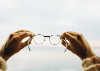 Two hands hold up a pair of glasses. Are you a victim of framing bias?