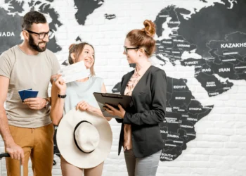 People stand in front of a huge world map. These insider booking tips can save you a bundle!
