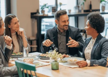 A group of people sit together eating lunch. They did their work lunch meal prep.