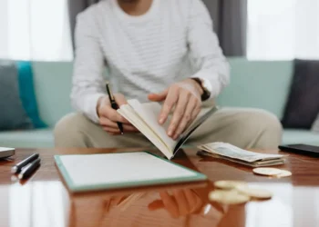 Person sits at a table flipping a financial trauma notebook.