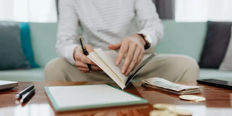 Person sits at a table flipping a financial trauma notebook.