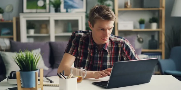 Man sits at desk, looking at laptop. The most important financial advice you need in your 40s starts here.