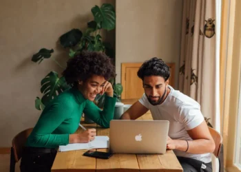 Man and woman look at an open laptop while improving their digital literacy.