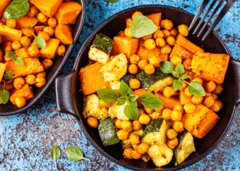A pan of Spiced Chickpea and Sweet Potato Salad on a blue background.