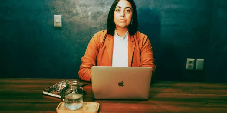 Professional woman sits at a desk in front of laptop.