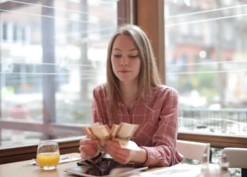 A young woman sits at a table counting money. Not being able to save is one of the financial issues facing millennials.