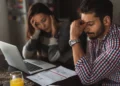 A man and woman look worried while looking at an open laptop. Money insecurity can be crippling.