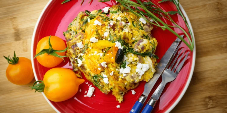 Red plate of vegetable frittata.