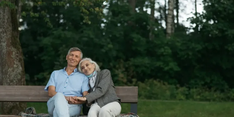 A retired couple rests on a bench together. What's the true cost of retirement?