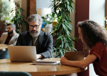 Man and woman sit at a desk together working. Planning is one of the most important financial things to know in your 60s.
