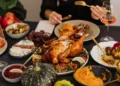 A beautiful Thanksgiving spread, with turkey and plates of food on a table.