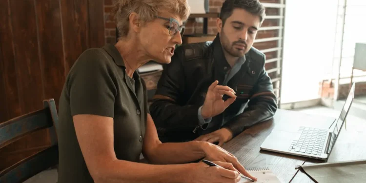 A woman and man sit at a desk together. Boost your earning potential comes back to communication.