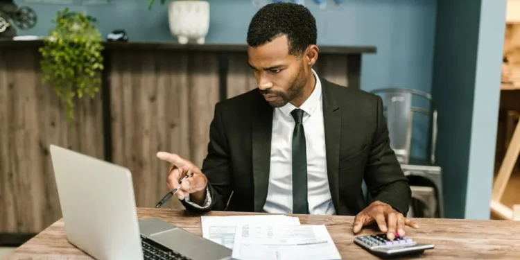 A man sits at a desk, looking at a hard credit inquiry on a computer screen.
