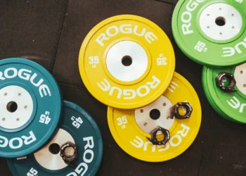 Green, blue and yellow weights fitness gear on a brown floor.