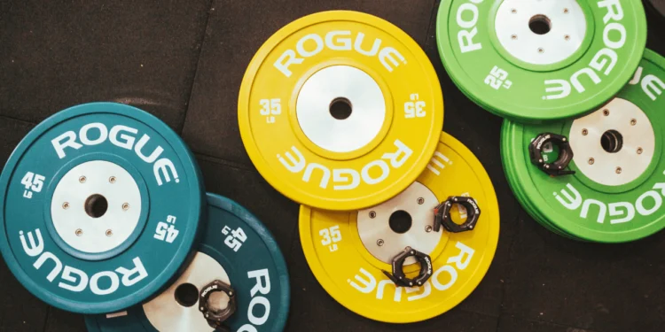 Green, blue and yellow weights fitness gear on a brown floor.