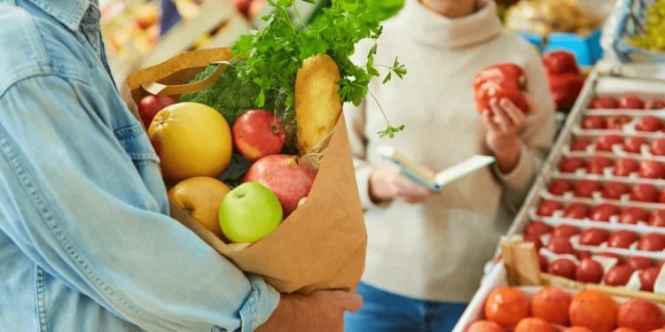 Person holds a bag of groceries in a store.