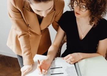 Two women look at a 401(k) vs. pension document together.