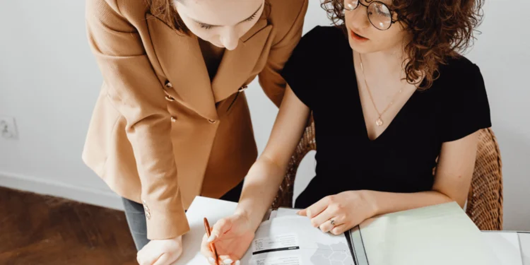 Two women look at a 401(k) vs. pension document together.
