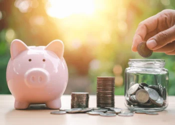 Pink piggy bank beside stacks of coins.