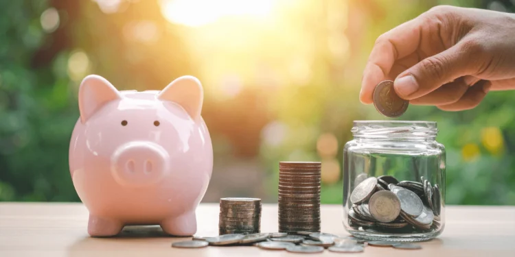 Pink piggy bank beside stacks of coins.
