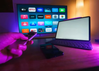 Hand holds a remote to a screen with streaming services.