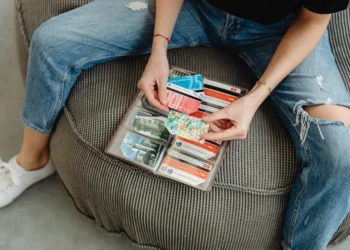 Person sits on chair, holding wallet full of colorful gift cards.