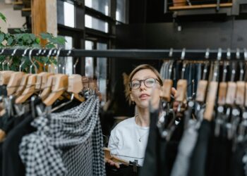 Retail worker puts away clothes on a rack in a store.