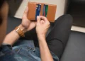 Man pulls cards out of a brown wallet.