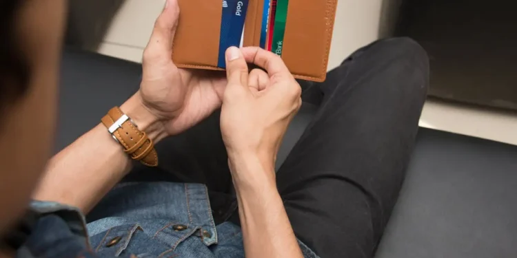 Man pulls cards out of a brown wallet.
