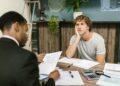 Overwhelmed man sits across desk from financial advisor.