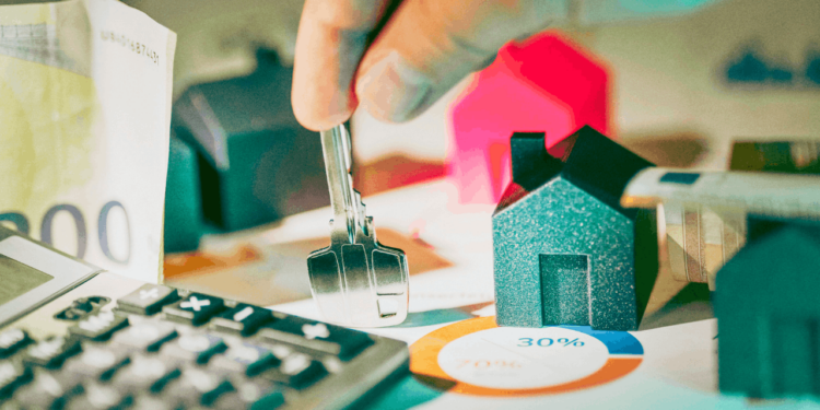 A hand holds a key on a messy desk.