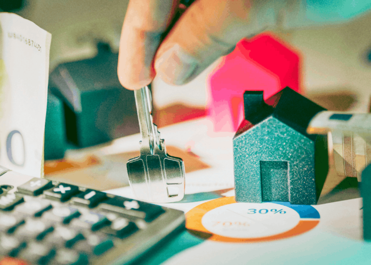 A hand holds a key on a messy desk.