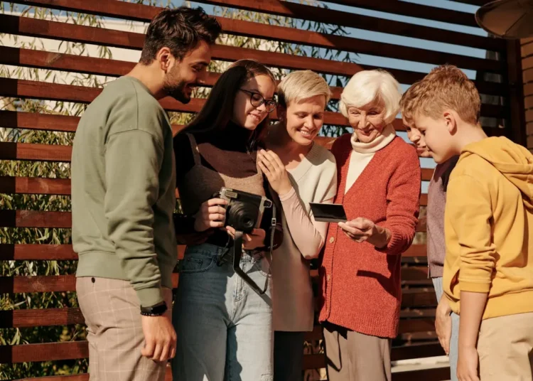 Multigenerational family with aging parents looks at a Polaroid together.